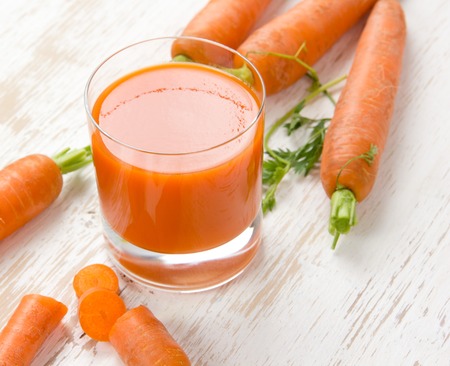 Photo of carrots and smoothie in a glass on white wooden boardの写真素材