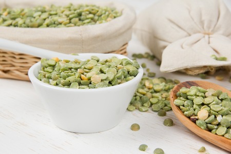 Photo of bowls full of lentil seeds on white wooden surface