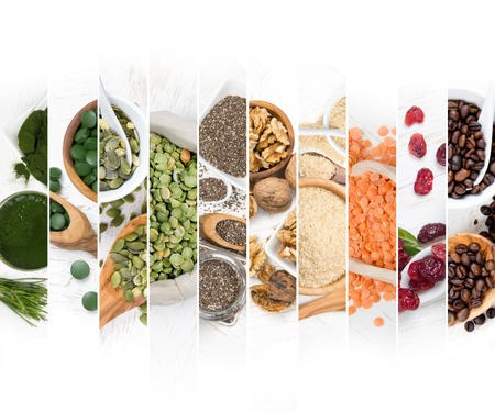 Top view of mixed colorful chlorella, berries, nuts and seeds scattered on white wooden surface;...