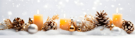 Golden Christmas candles, balls and pine cones in a row with spruce branches covered with snow and snowfall on white background in winter. Horizontal composition.の素材