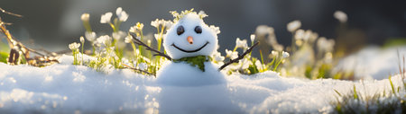 Snowman on a meadow with grass and spring flowers growing through the melting snow. Concept of spring coming and winter leaving.の素材