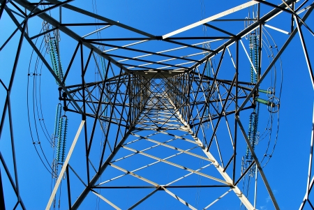 High voltage electricity pylon from the ground up against blue skyの写真素材