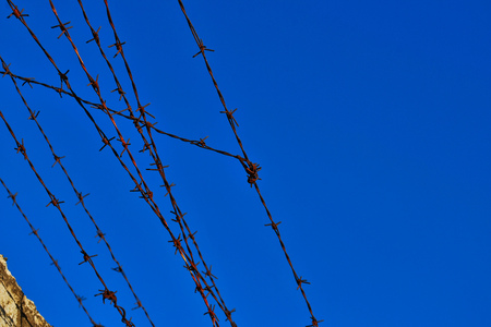 Old rusty barbed wire fence atop concrete wallの写真素材