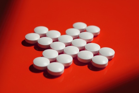 White cross from tablets on a red backgroundの写真素材