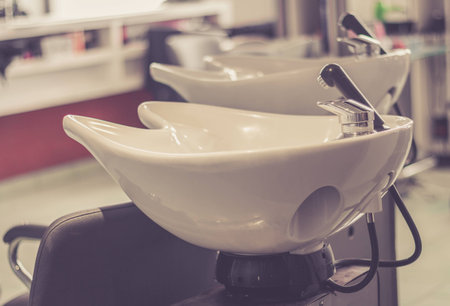 Beauty salon interior - a row of hair washing sinks - white washbasins for hairdresserの写真素材