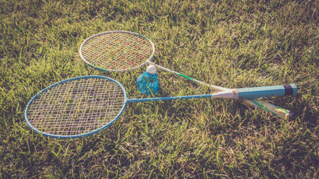 Shuttlecock and badminton rackets outdoor on green grass