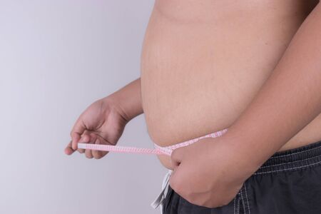 Fat man check out his body fat with measuring tape. obesity and Health care concept.の写真素材