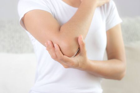 Close up woman having pain in injured elbow. Health care and arm pain concept.