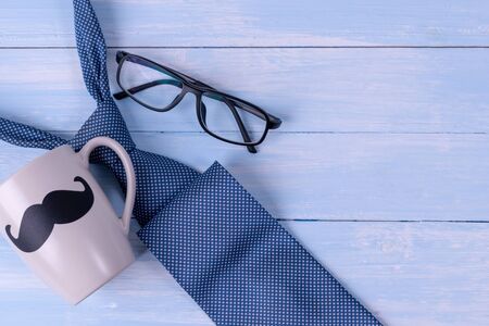 Happy fathers day concept. Top view of father's accessories coffee, tie and glasses on pale blue wooden background.の写真素材
