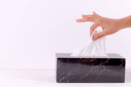Healthcare concept. Woman hand picking white tissue paper from tissue box. Copy space for advertisers.の写真素材