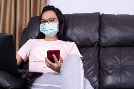 Coronavirus or Covid-19 concept. Business woman working from home wearing protective mask. Business woman in quarantine for coronavirus wearing protective mask. Working from homeの写真素材
