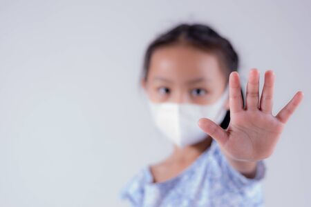 Little girl wearing mask for protect covid-19 and show stop hands gesture for stop coronavirus outbreak. Coronavirus conceptの写真素材