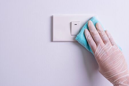 Woman hand to clean light switches protect Coronavirus or Covid-19. Copy space.