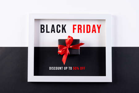 Gifts and white photo frame on black and white paper background. Black Friday concept.