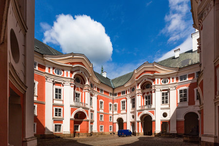 Broumov, Czech Republic - June 17 2020: Courtyard of the famous Benedictine monastery with red and white facade. Sunny summer day with blue sky and white clouds.のeditorial素材