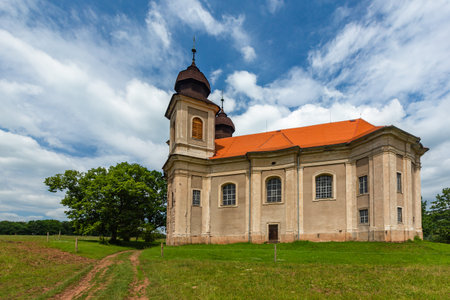 Sonov, Czech Republic - June 17 2020: Rural landscape with baroque church of St Margaret with two towers standing on a hill with green grass. Sunny summer day with blue sky and white clouds.のeditorial素材