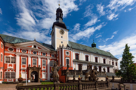 Broumov, Czech Republic - June 17 2020: The Benedictine monastery with red and white facade and the church of St Adalbert from 14th century. Sunny summer day with blue sky and white clouds.のeditorial素材