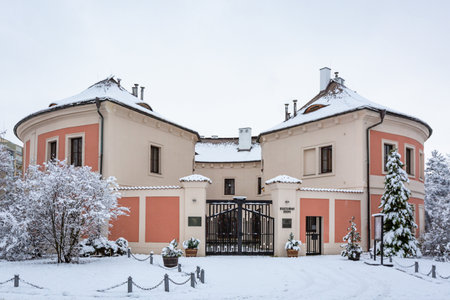 Prague, Czech Republic - January 7 2021: Front view of the Chodov fortress with red and pink facade standing in a park. Cloudy winter day with white snow covering ground and trees.のeditorial素材