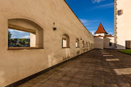 Jindrichuv Hradec, Czech Republic - September 26 2019: View of the surrounding wall with windows and little tower belonging to the castle. Tile paving on the ground. Sunny autumn day with blue sky.のeditorial素材