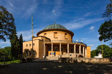 Prague, Czech Republic - May 23 2019: A round orange Planetarium building surrounded by trees standing in a park called Stromovka. Bright sunny spring day with blue sky.のeditorial素材