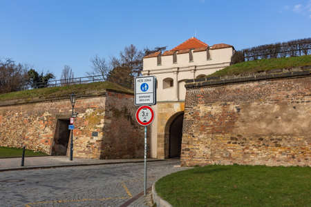 Prague, Czech Republic - March 26 2021: View of the Tabor gate and a stone wall, a part of fortification, at Vysehrad, cobblestone street, green lawn on a sunny day with blue sky.のeditorial素材