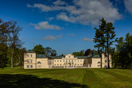 Lazne Kynzvart, Czech Republic - May 31 2021: View of the castle, a yellow building standing in a park. Green grass in the foreground and trees around. Sunny spring day with blue sky and clouds.のeditorial素材