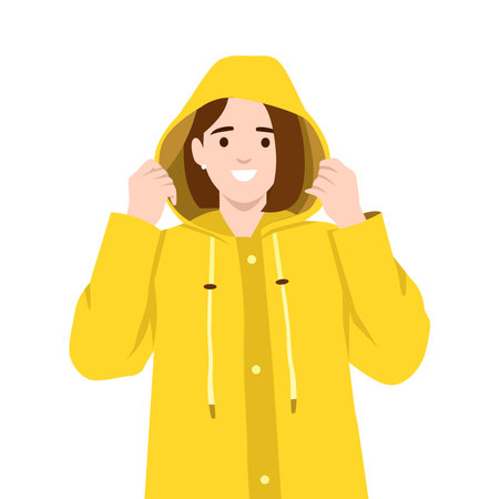 Smiling woman adjusts the hood of her yellow raincoat, prepared to face the rainy weather. Flat vector illustration isolated on white backgroundのイラスト素材