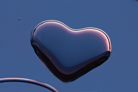 drop of water in a heart shape with the reflection of the sunset skyの写真素材