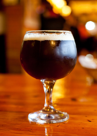 Glass of dark Belgian beer on a wooden tableの写真素材