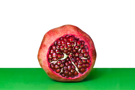 Open Pomegranate with seeds on white and green の写真素材