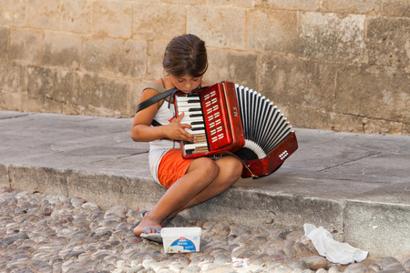 young child beggar, playing music in the streets of Athens, Greece, with peopleのeditorial素材