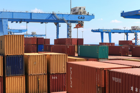 Various brands and colors of shipping containers stacked in a holding platform waiting for loading