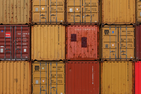 Various brands and colors of shipping containers stacked in a holding platform waiting for loadingのeditorial素材