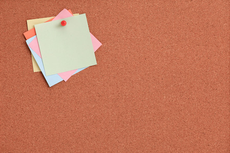 Cork board with colorful notes and red pin