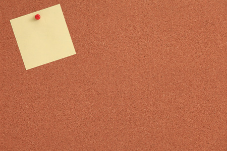 Cork board with yellow note and red pinの写真素材