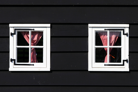 Two white windows with red checkered curtainsの写真素材