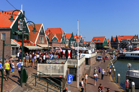 Tourists and locals at Volendam's boardwalk. Volendam is a famous small town attraction thanks to its traditional costumes, port and seaside restaurants.のeditorial素材