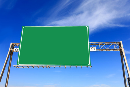 Green highway sign with blue sky in the background
