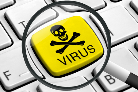 Computer keyboard with yellow virus button and magnifying glassの写真素材