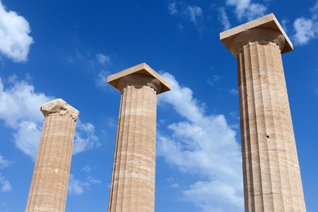 Ancient Greek pillars at the Athens acropolis with blue cloudy sky in the background