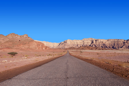 Empty desert road with mountains and blue sky in the backgroundの写真素材