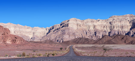 Empty desert road with mountains and blue sky in the backgroundの写真素材