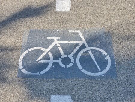 White Bicycle lane mark on an Asphalt road with palm tree shade.の写真素材