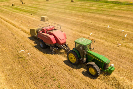 John Deere tractor and Baler discharging a Hay Bale, Aerial