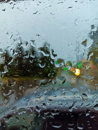 Raindrops on the wet, misted glass. Raindrops on the background of bright yellow lights, raindrops on the glassの写真素材