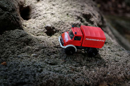 A red firefighting toy truck is placed on the surface of irregular bumpy rock formed by volcanic eruptionの写真素材