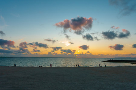 Beautiful sunset at the seaside with people in groups of three or twoの写真素材