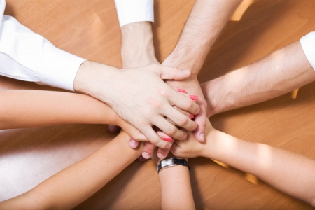 Office workers hold hands together on tableの写真素材