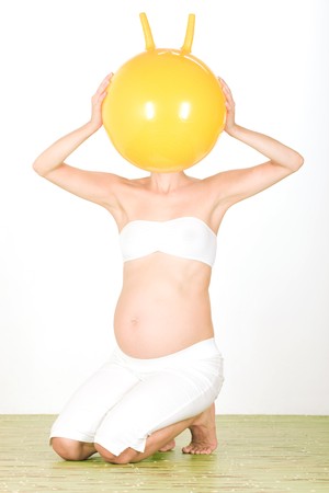 Studio portrait of pregnant woman with ball across headの写真素材