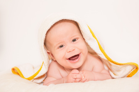 Pretty newborn baby smiling on white towelの写真素材